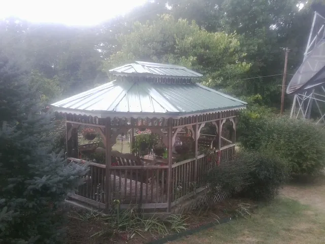 Green metal roof on a backyard gazebo surrounded by garden beds in Maitland