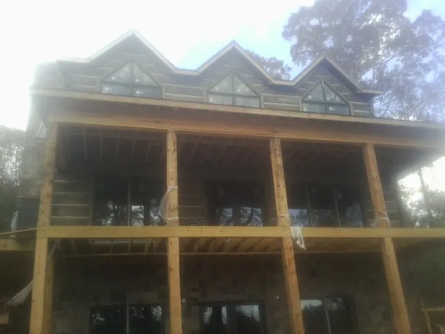 Dormers and porch framing on a large log home under construction — Roof Coating work by our crew in Maitland
